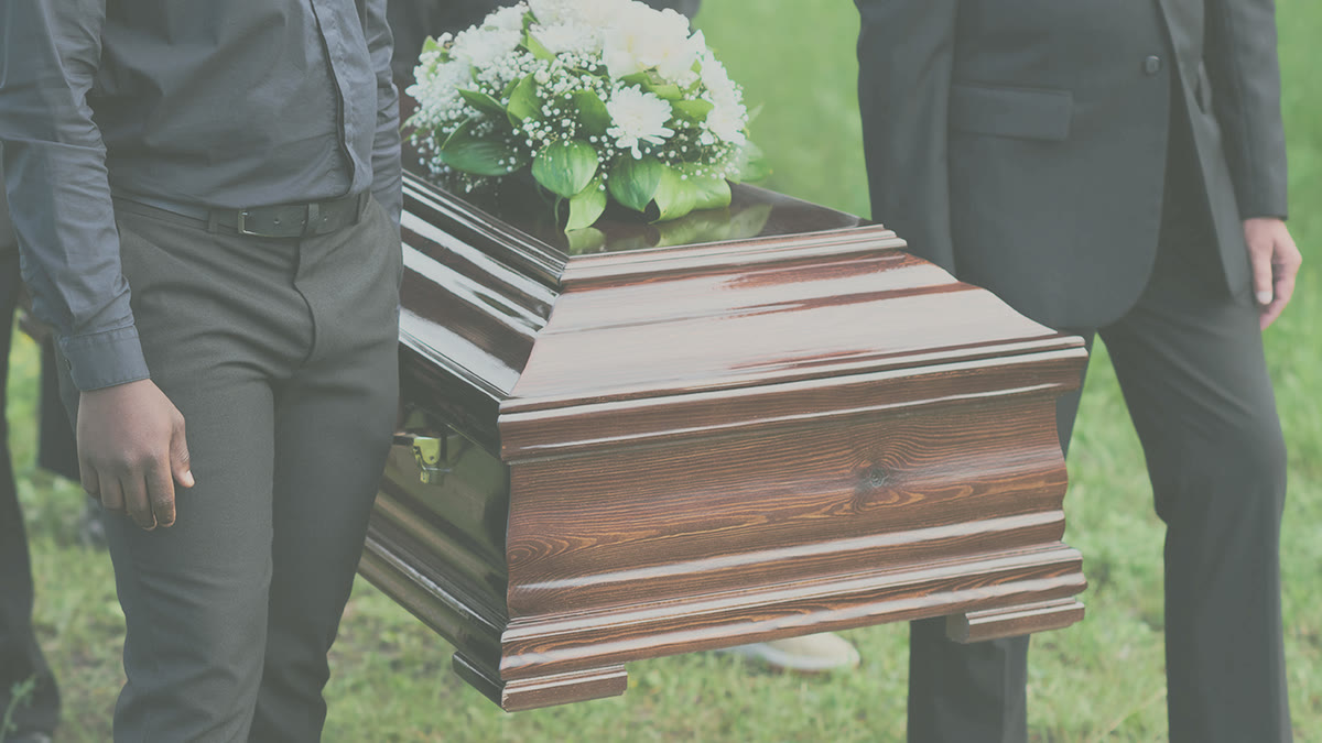 Pallbearers carrying a casket dressed with white flowers