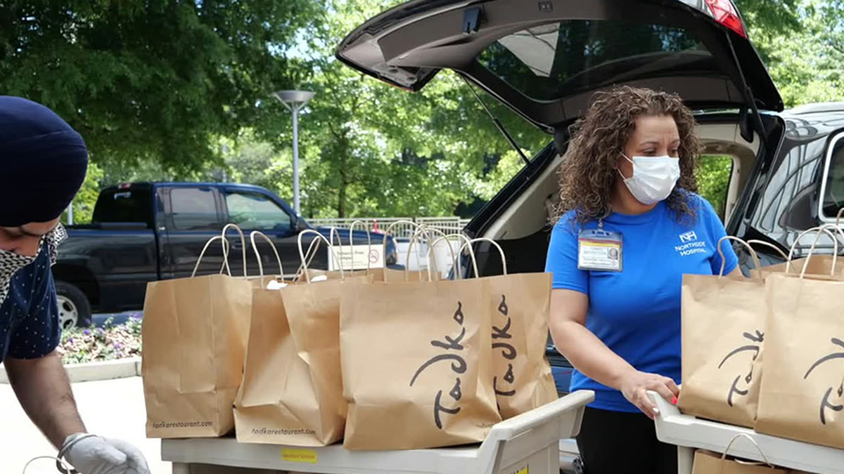 NSO volunteers loading bags of prepared meals into a car for hospital staff